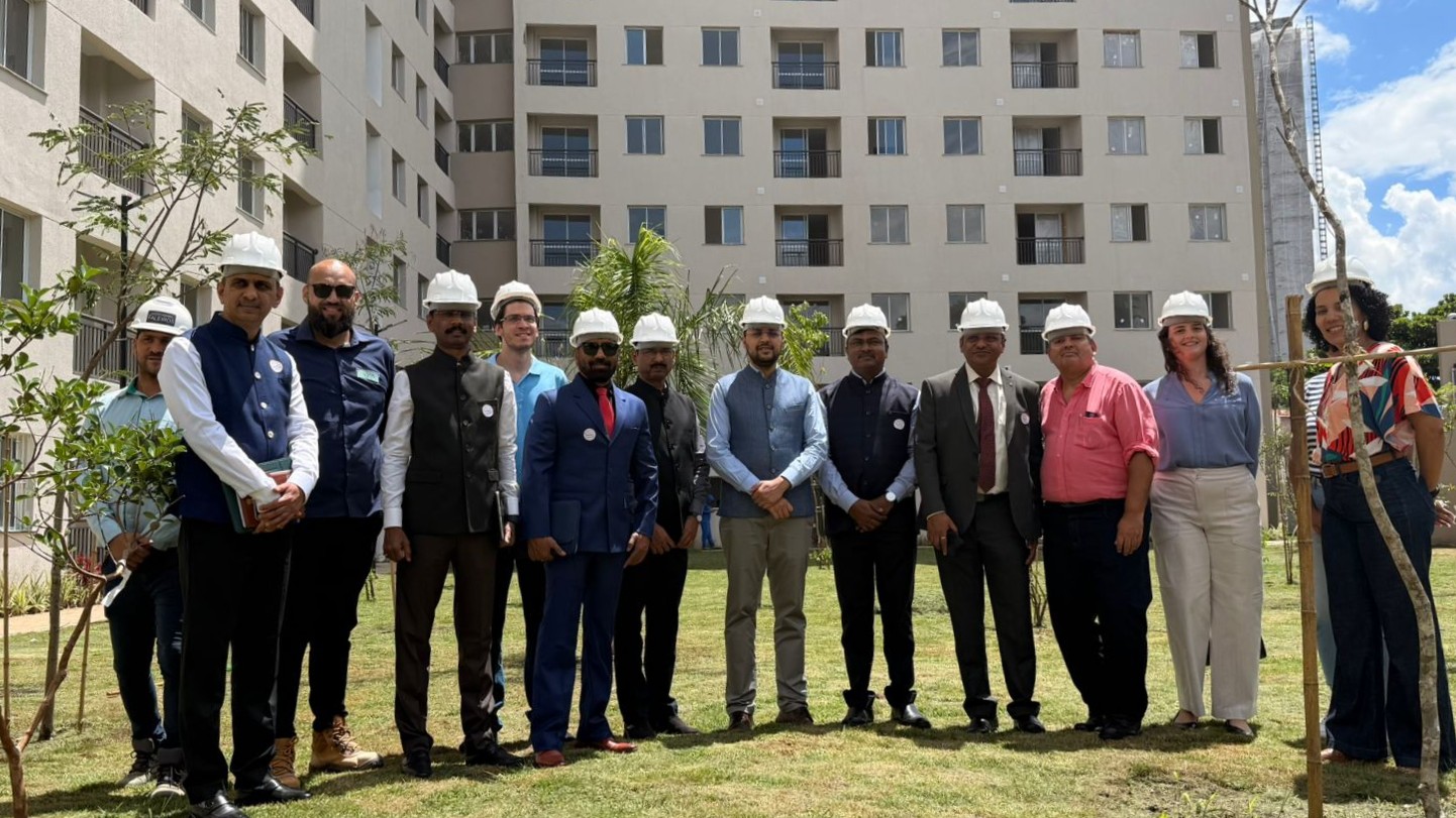 Integrantes da Comitiva do Governo do Estado de Maharashtra junto da equipe de SEHAB posam lado a lado para foto em gramado em frente ao empreendimento Bresser VI