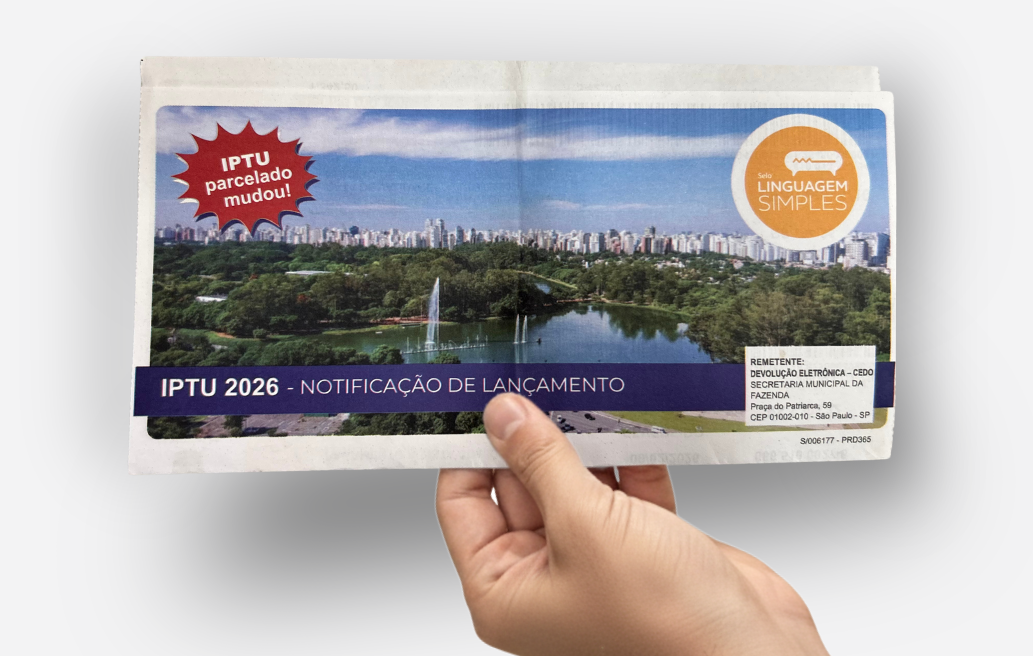 Uma mão segurando um carnê de IPTU